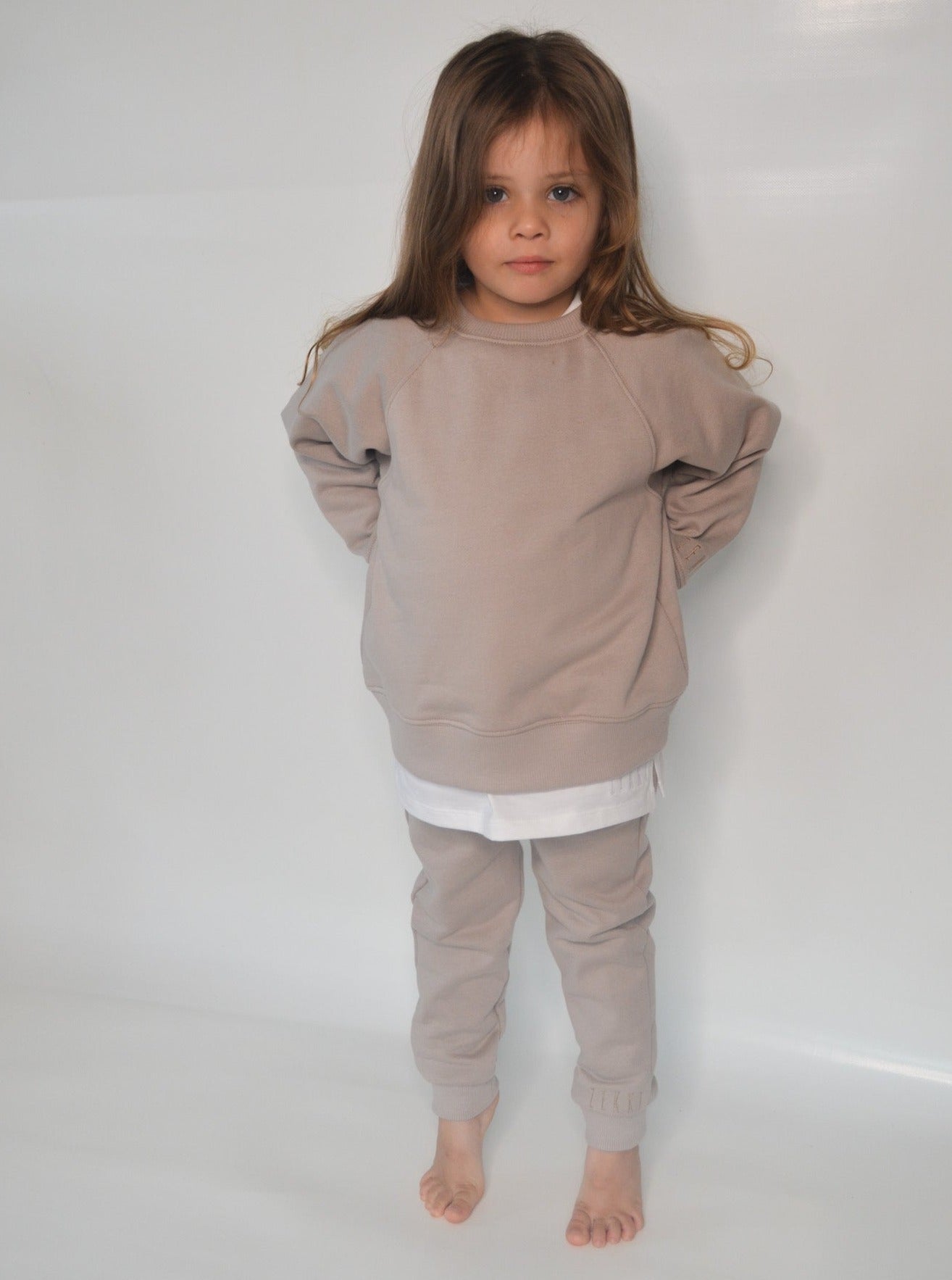 Girl wearing smokey colour batwing jumper with white longline t-shirt and smokey colour trackpants