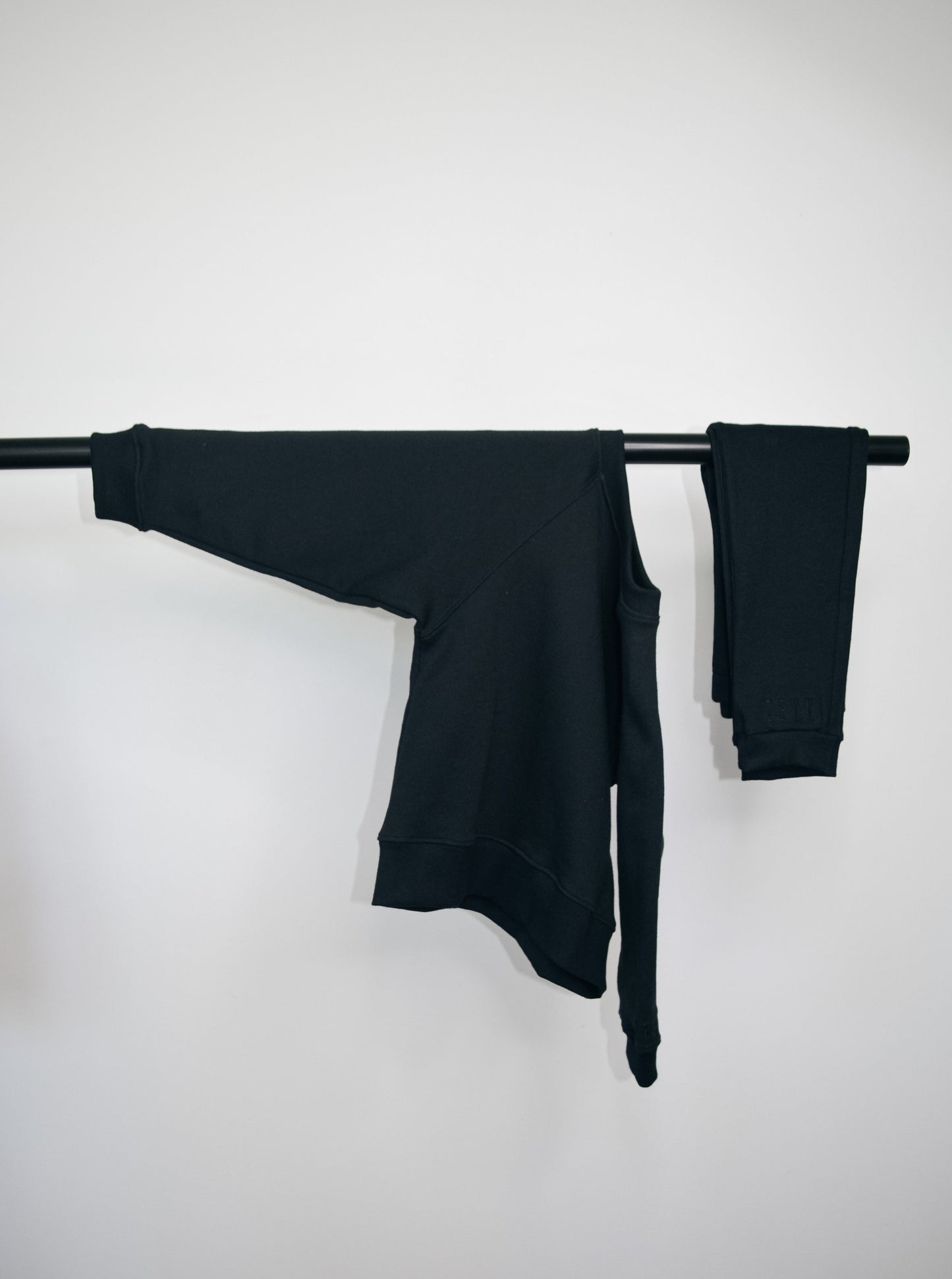 Black batwing jumper and black loose legging hanging on bar