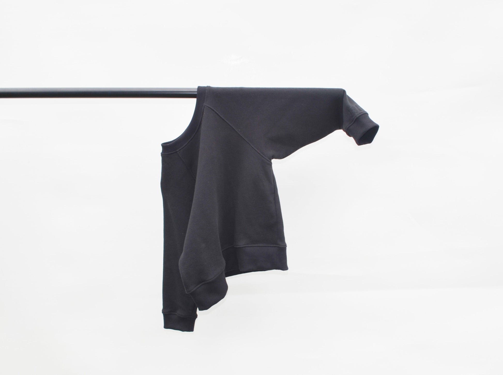 Black batwing jumper hanging over pole
