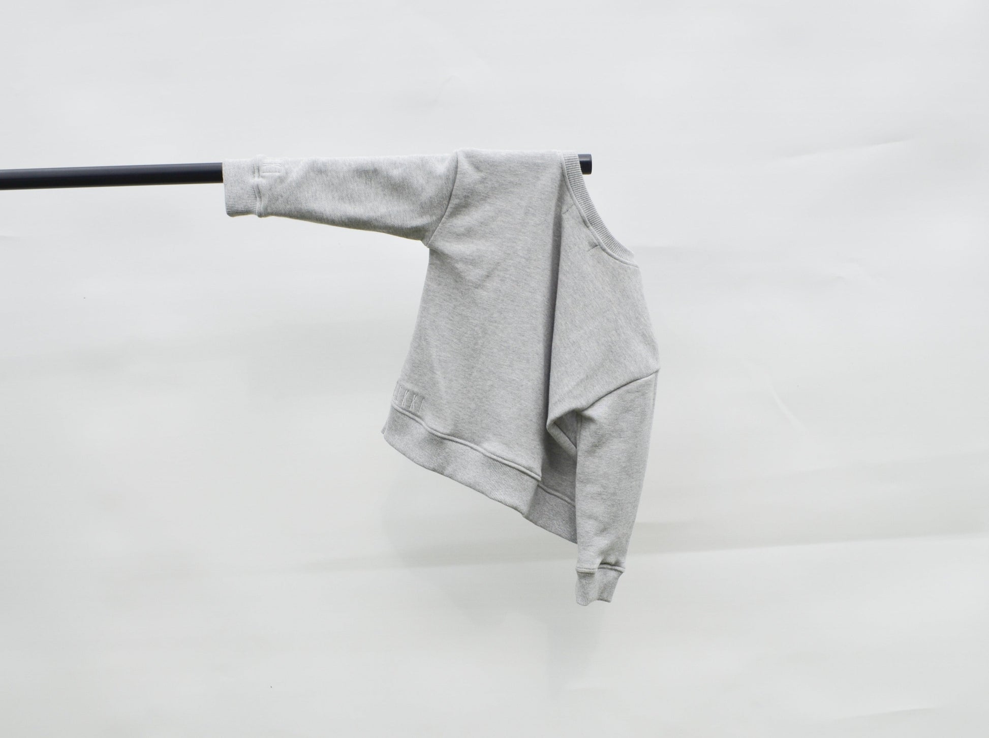 back of Grey longline jumper hanging on a pole