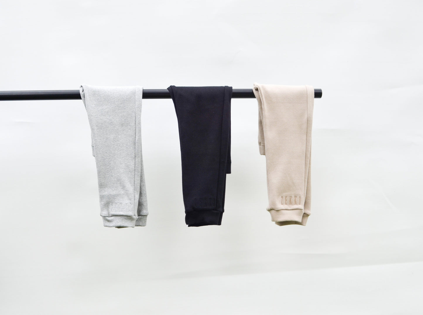 Grey, black and smokey colour casual pants hanging over pole