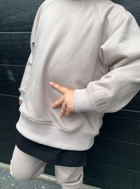 Girl wearing smokey colour batwing jumper with black longline t-shirt and smokey colour trackpants. 