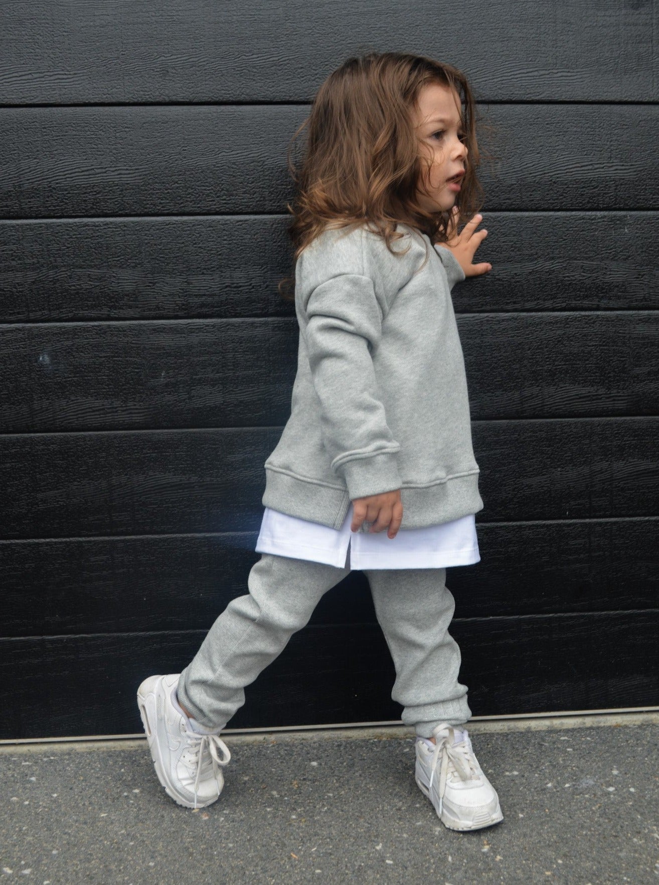 Boy wearing grey longline jumper, wearing white longline t-shirt and grey loose legging