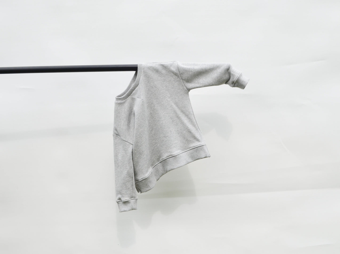 Grey longline jumper hanging on a pole