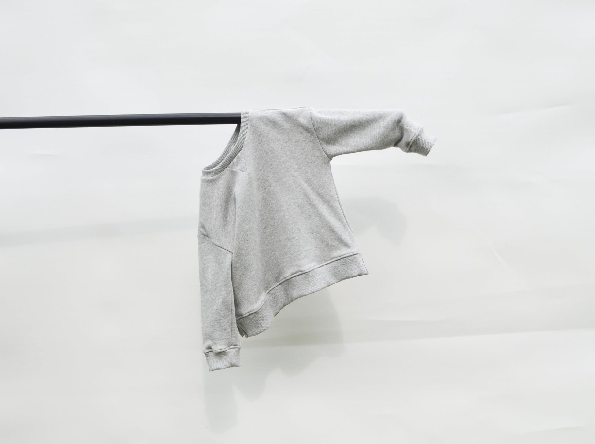 Grey longline jumper hanging on a pole