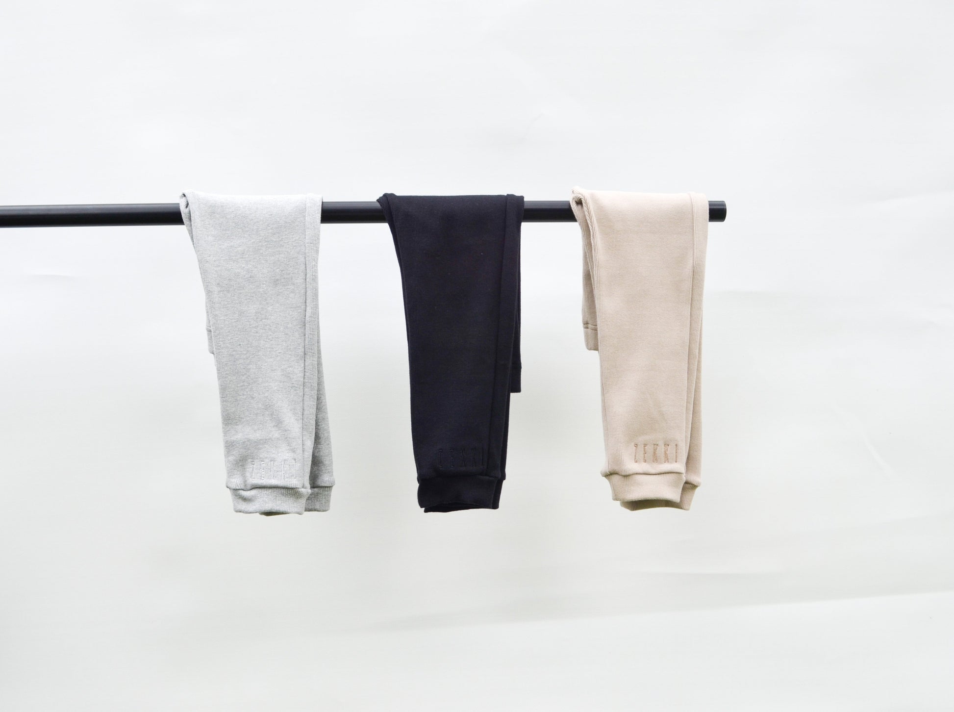 Grey, black and smokey colour casual pants hanging over pole