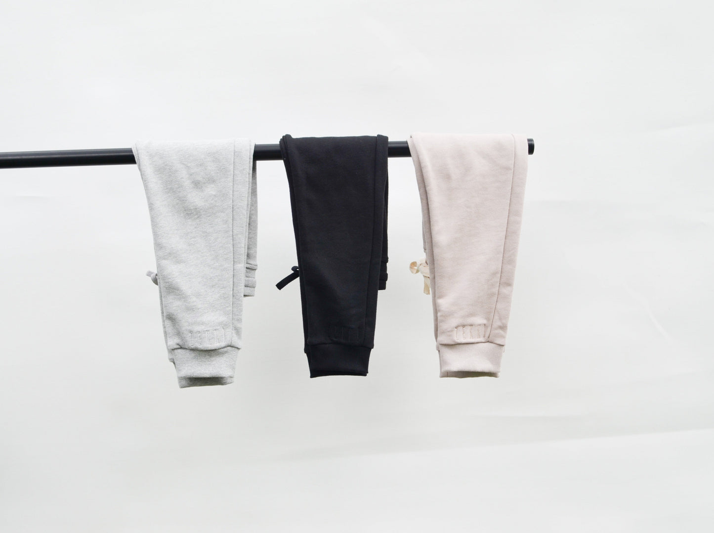 Grey, black and smokey track pants hanging over bar 