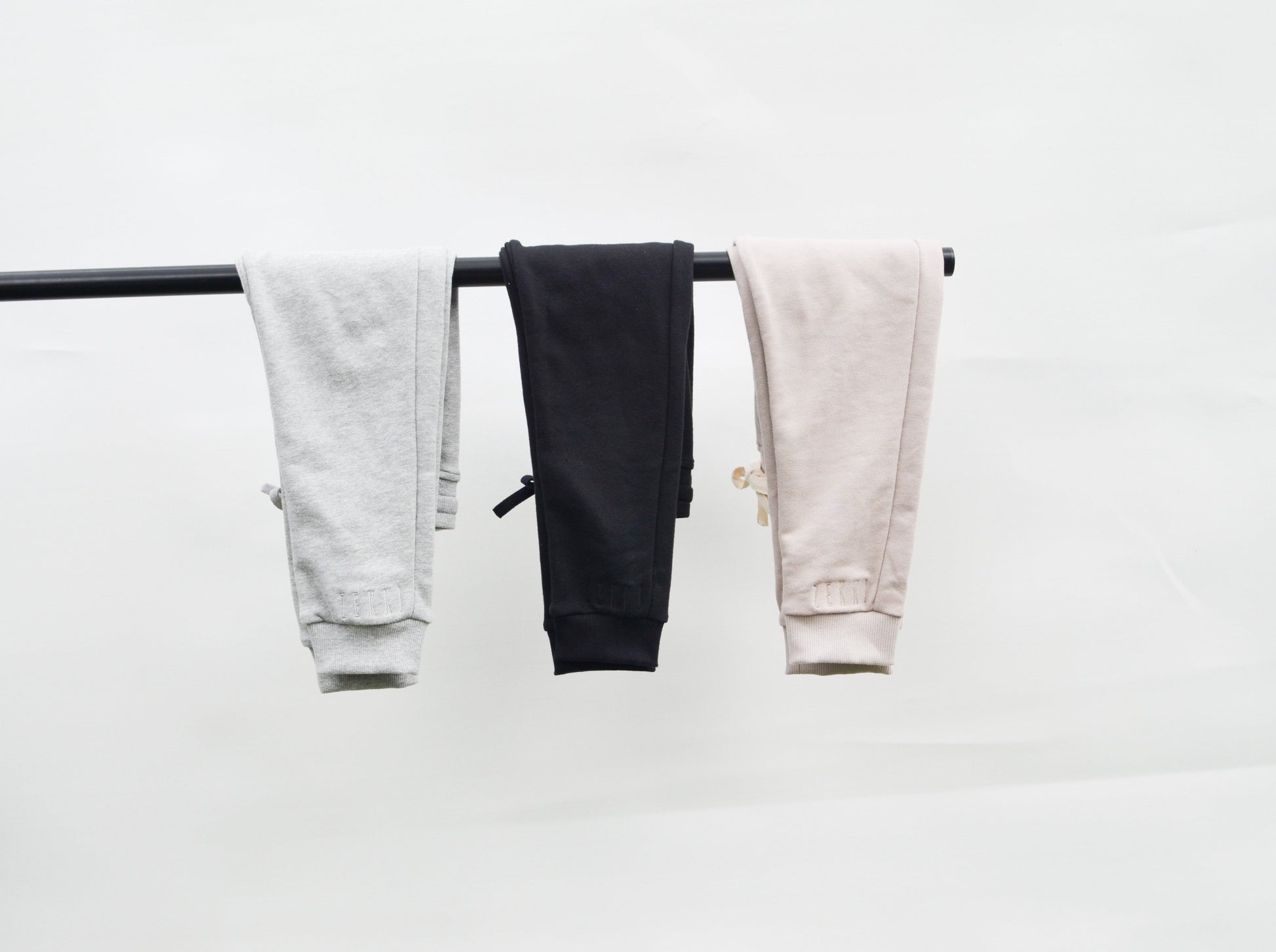 Grey, black and smokey track pants hanging over bar 