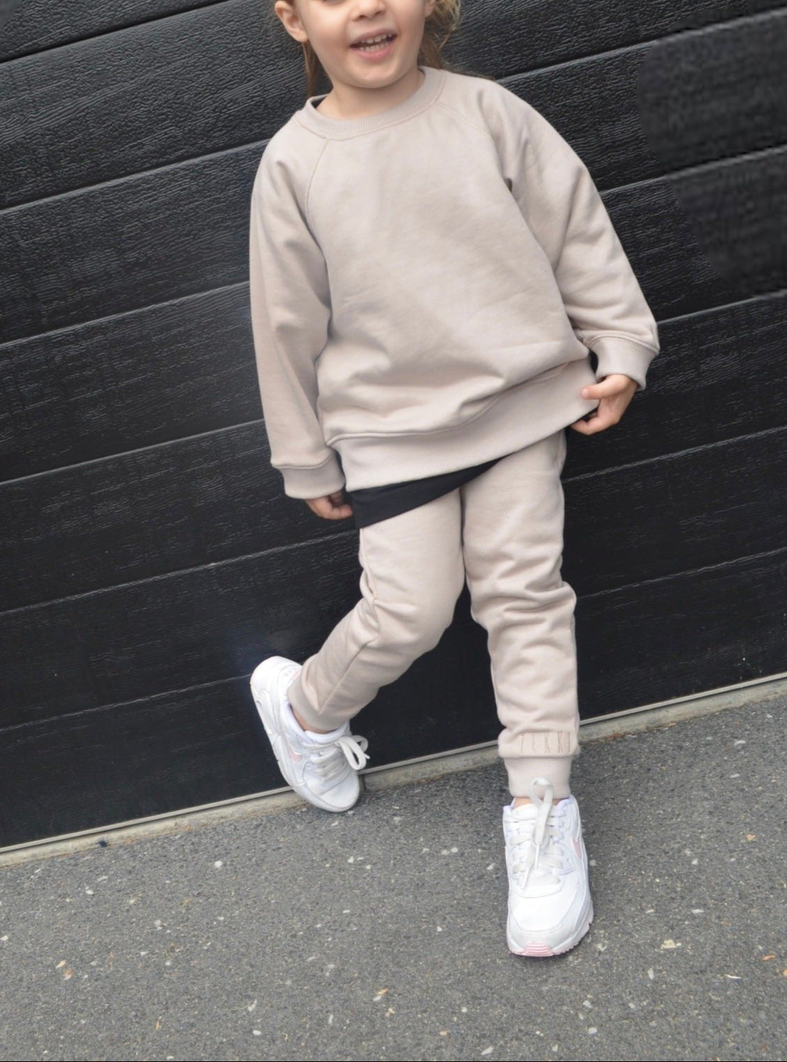 Girl wearing smokey colour batwing jumper with black longline t-shirt and smokey colour trackpants.