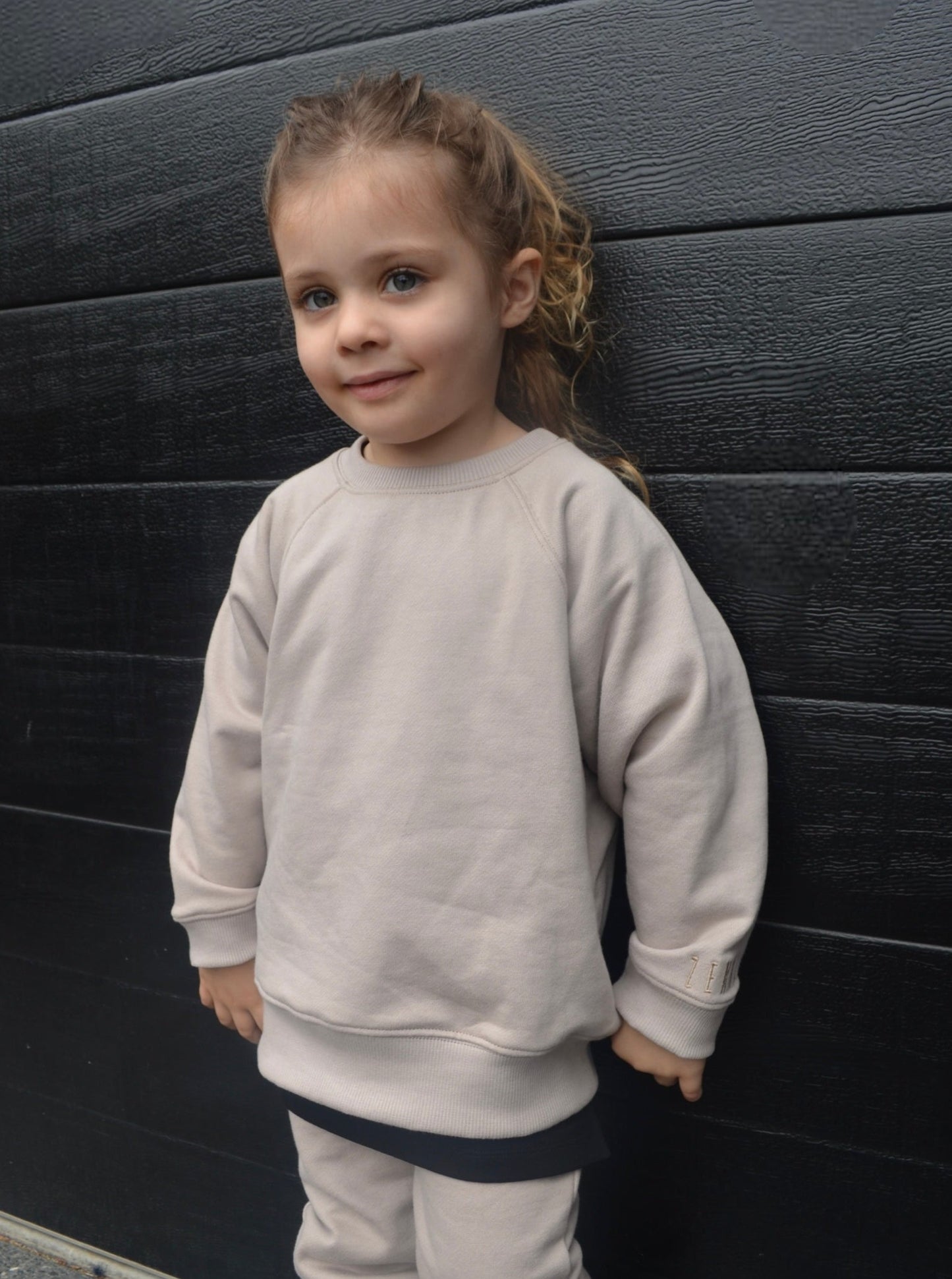 Girl wearing smokey colour batwing jumper with black longline t-shirt and smokey colour trackpants.