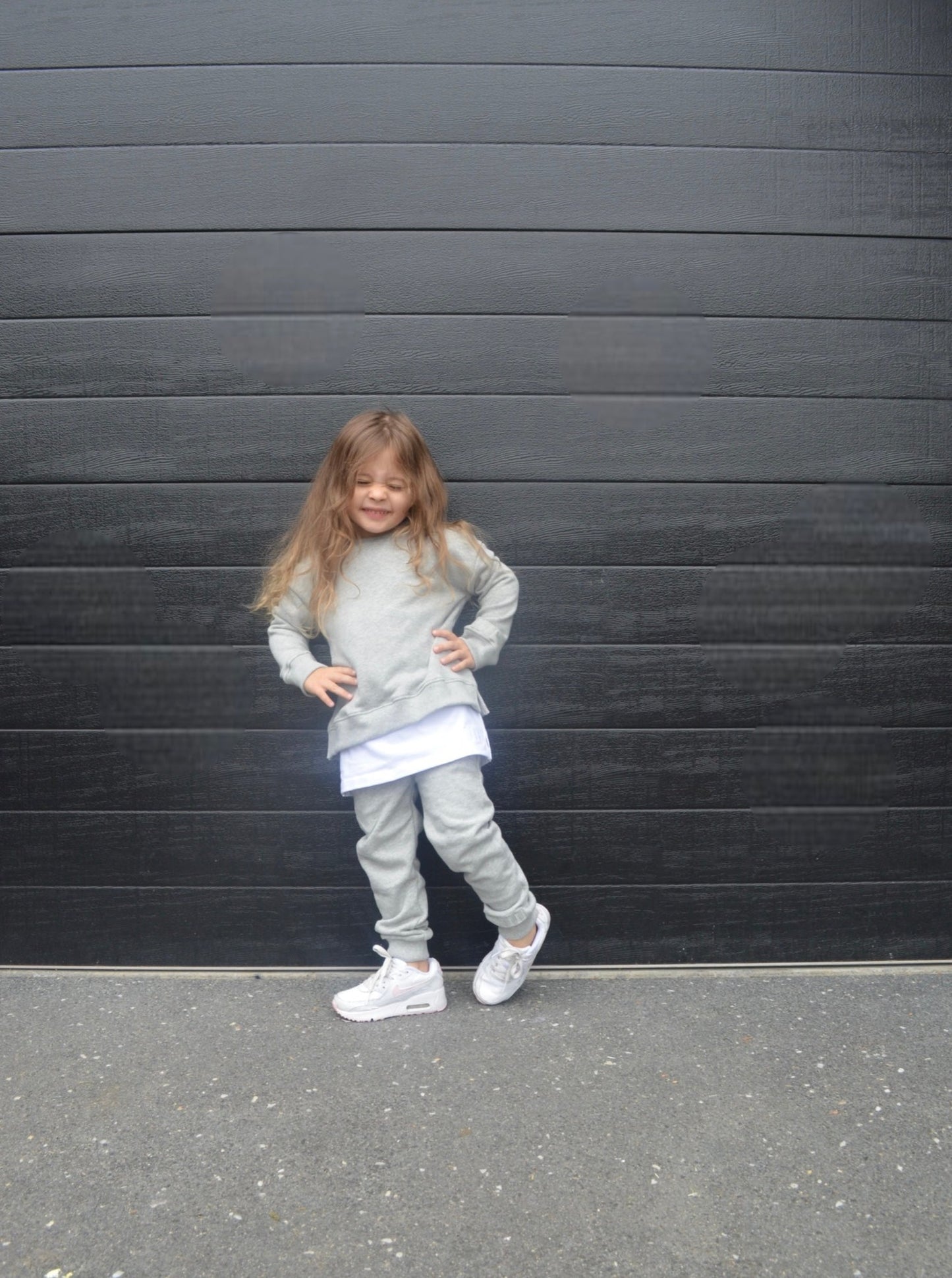 Girl wearing grey colour longline jumper with white longline t-shirt and grey colour track pants.